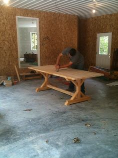 a man is working on a table in the middle of a room with plywood walls