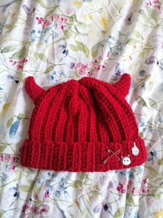 a red knitted hat laying on top of a bed