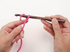 two hands crocheting the end of a pink yarn