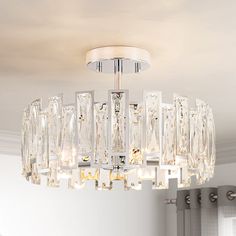 a crystal chandelier hanging from the ceiling in a room with white walls and windows