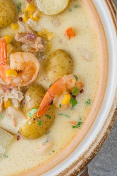 a bowl filled with shrimp, potatoes and carrots