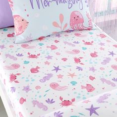 a bed with pink and purple sea animals on it, along with two pillow cases