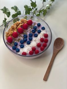 a bowl filled with cereal and berries next to a spoon