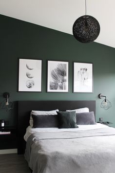 a bedroom with green walls and pictures on the wall above the bed, along with two lamps