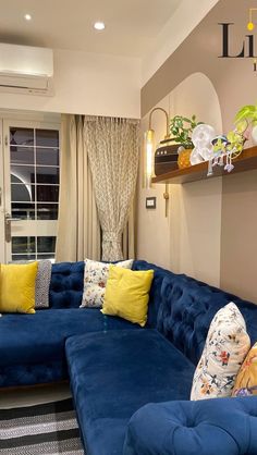 a living room with blue couches and yellow pillows on the back of each couch