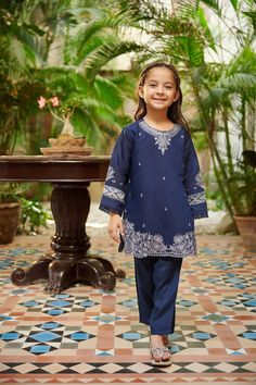 2-Piece Embroidered Suit for Girls (shirt & trouser only) : Intricately crafted two-piece design with elegant beaded and embroidered details with a hint of mirror embellishment. Description -- Kameez (Shirt) : Paper Cotton shirt. Lining included. -- Shalwar (Trouser) : Navy Blue Pants. General Care Instruction : Should be hand washed and hung to dry. Color may bleed so please be mindful of other items with it. General Disclaimer -- Size chart provides reference sizes and actual sizes might be sl Pakistani Kids Dresses Eid, Traditional Blue Pant Set With Floral Embroidery, Blue Embroidered Long Sleeve Pant Set, Elegant Blue Embroidered Pant Set, Festive Embroidered Blue Pant Set, Festive Blue Embroidered Pant Set, Fitted Blue Embroidered Pant Set, Blue Cotton Sets With Intricate Embroidery, Embroidered Cotton Pant Set For Eid