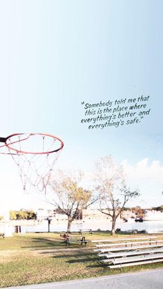 a basketball hoop is in the air above some benches and trees, with a quote written on it