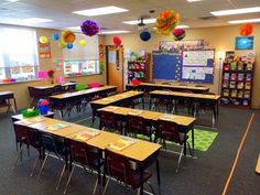 an empty classroom with desks, chairs and decorations on the walls in front of windows