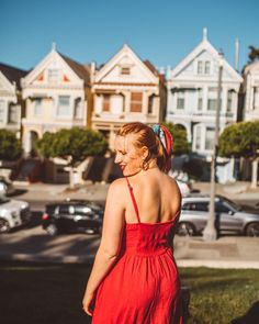 a woman in a red dress is walking down the street with her back to the camera