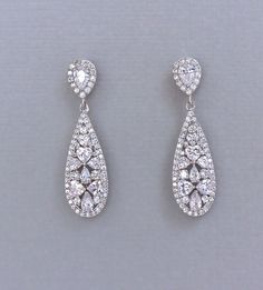 two pairs of diamond earrings on a gray background with clippings to the side