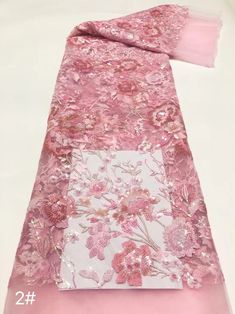 a pink and white scarf with floral designs on it's side, sitting on a table