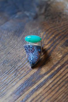 This ring is decorated with an alluring combination of all natural vivid and glowing gems. A striking bright green bubbly Australian chrysoprase glows while sitting beside a rich in color crystalized Petrified Wood, stark and playful in pattern.  One of a kind for their amazing organic palette and patterns. Ring is entirely hand formed, forged and built from raw sterling sheet. Curved to cradle your finger and tapered at the back for a comfortable fit. Fits like a standard ring.  Fits size 10. Organic Palette, Glow Ring, Petrified Wood, Multi Stone Ring, Beautiful One, Multi Stone, Bright Green, Stone Rings, Hand Stamped