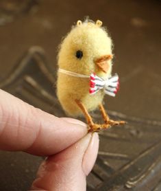 a tiny yellow bird sitting on top of a persons finger