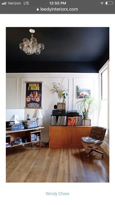 a living room with hard wood floors and white walls, an old record player on the sideboard