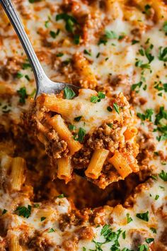 a close up of a spoon full of pasta and meat sauce with parsley on top