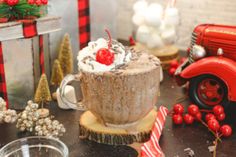 a table topped with a cup filled with ice cream next to christmas decorations and gifts