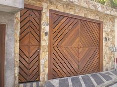 two wooden garage doors on the side of a stone building with words made west above them