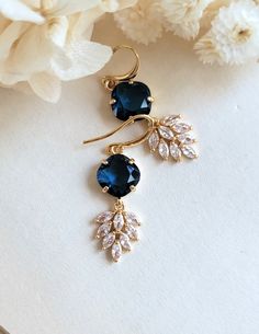 Gorgeous vintage inspired Art deco earrings. Faceted navy blue faceted cushion glass encased in gold setting; dangling below are intricate marquise cut cubic zirconia feather charm.  On gold plated brass settings and ear wires.  Simply stunning!! Total length: 43 mm Drop length: 33 mm Blue glass: 11*11 mm CZ drop: 16*12 mm Purchase over $40 enjoys free shipping! Coupon code 'freeshipping1'. Free Gift Wrapping on request - All items that are gift wrapped come in with a kraft box with raffia string and blank writing card.  Please leave a note if you need it upon ordering. Blue Art Deco Jewelry For Jewelry Making, Blue Gold Bridal Earrings, Elegant Sapphire Jewelry With Ear Wire, Blue Art Deco Jewelry For Party, Blue Art Deco Jewelry For Wedding, Blue Art Deco Jewelry For Evening, Blue Elegant Luxury Teardrop Earrings, Blue Art Deco Wedding Earrings, Blue Intricate Design Drop Earrings