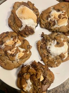 four cookies with ice cream and chocolate chips on a white plate, ready to be eaten