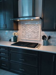 a stove top oven sitting inside of a kitchen next to black cupboards and white counter tops