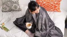 a man sitting on top of a bed holding a cup of coffee