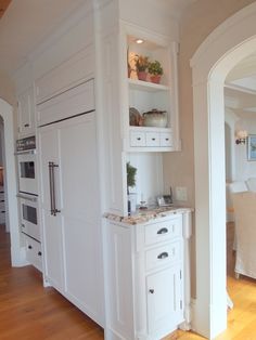 a kitchen with white cabinets and marble counter tops