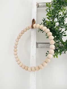 a wooden beaded necklace hanging on a wall next to a potted green plant