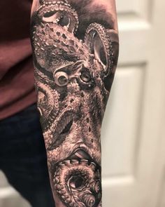 an octopus and squid tattoo on the right arm, done in black and grey ink