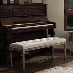 a piano and bench in a living room with a rug on the floor next to it