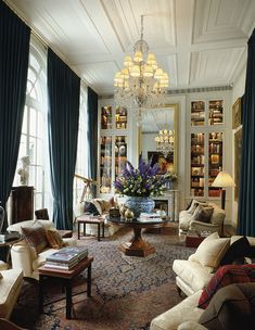 a living room filled with lots of furniture and a chandelier hanging from the ceiling