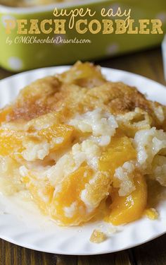 a slice of peach cobbler on a white plate next to a green casserole dish