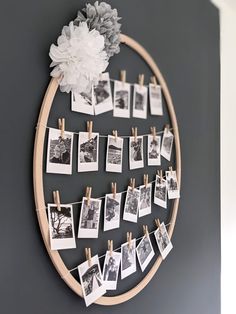 a wooden circle with pictures hanging on clothes pegs and a white flower in the center