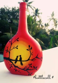 a red vase with two birds sitting on a tree branch in front of the sun