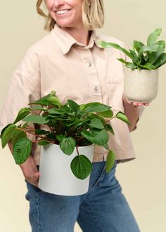 a woman holding a potted plant and smiling