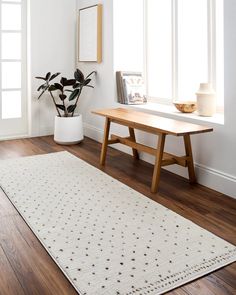 a wooden table sitting next to a white rug on top of a hard wood floor