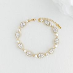 "A dainty and sparkling tear drop gold wedding bracelet for the bride with cubic zirconia and pearls. Adorned with shimmering crystals and lustrous pearls the bridal bracelet has a combination of halo set teardrop cubic zirconia crystals and small shell white pearls, finished off with a lobster clasp and an extension chain. Material used is 14k gold plated brass. Also available in rhodium/silver plated and rose gold plated finish. This bracelet is the perfect accessory for the bride, slim and el Gold Cubic Zirconia Crystal Bracelet For Wedding, Pear-shaped Silver Bracelet For Weddings, Delicate Gold Crystal Bracelet For Wedding, Dainty Gold Diamond Bracelet For Wedding, Gold Pearl Bracelet For Wedding, Elegant Pear-shaped Bracelets For Wedding, Elegant Pear-shaped Bracelet For Wedding, Gold Wedding Bracelet, Gold Bracelet Wedding