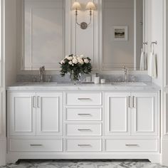 a white bathroom with marble counter tops and double sinks