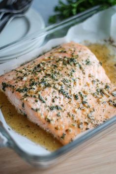 a close up of a piece of salmon in a glass dish on a wooden table