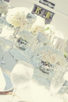 the table is set up with white flowers and wine glasses for an elegant wedding reception