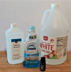 three bottles of white vinegar and one bottle of baking soda on a wooden countertop