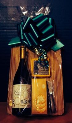 a bottle of wine, crackers and cookies in a wooden box with a green bow