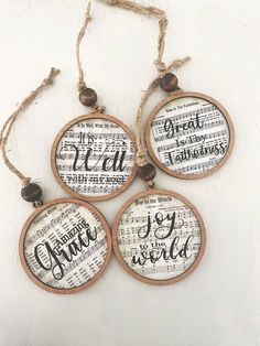 four ornaments with words on them hanging from string