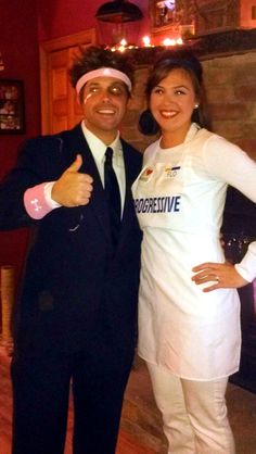 a man and woman pose for a photo in front of a fire place with their thumbs up