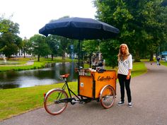 a woman standing next to a bike with an ice cream cart on the front and side