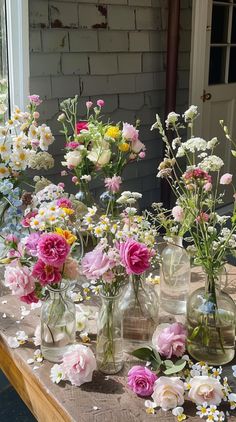 a table topped with lots of vases filled with different types of wildflowers