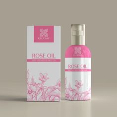 a bottle of rose oil next to a box on a gray background with pink flowers