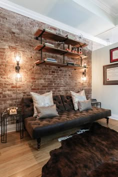 a living room with brick walls and leather furniture in the center, along with shelving