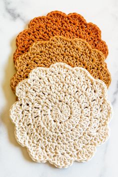 four crocheted coasters on a marble surface