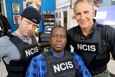 three men standing next to each other wearing police vests