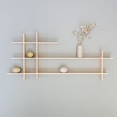 three shelves with vases, rocks and flowers on them against a gray wall background